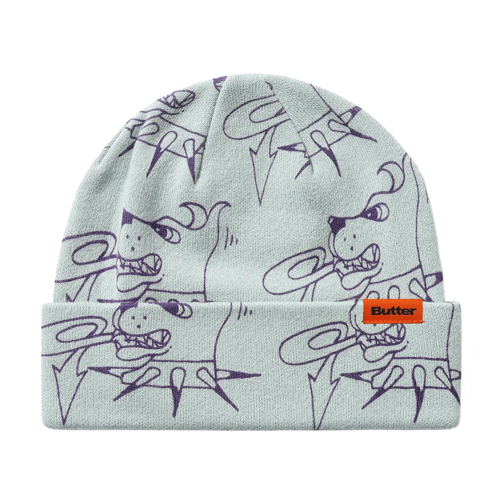 The Butter Goods BUTTER CANINE BEANIE GREY features a light gray knit, playful purple cartoon doodle pattern, and an orange "Butter" label on the front cuff—adding fun to your winter style.