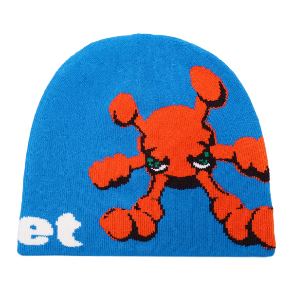 The blue CARPET CO. BACTERIA REVERSIBLE BEANIE by Carpet Co. features an orange cartoon character with green eyes and the partial text "et" on the left side, branded with a subtle BEANIE GREEN tag.