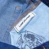 Close-up of a POLAR CARPET CO. C-STAR JEANS WASHED BLUE, showing an inner label reading "Lose yourself." Beneath the label is a partial character illustration, showcasing the craftsmanship in its cotton fabric.