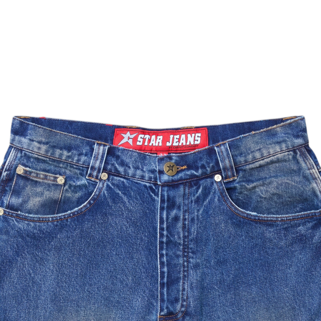 Close-up of washed blue denim jeans with the red "Polar" label on the waistband, reading "CARPET CO. C-STAR JEANS," crafted from premium cotton for comfort and style.