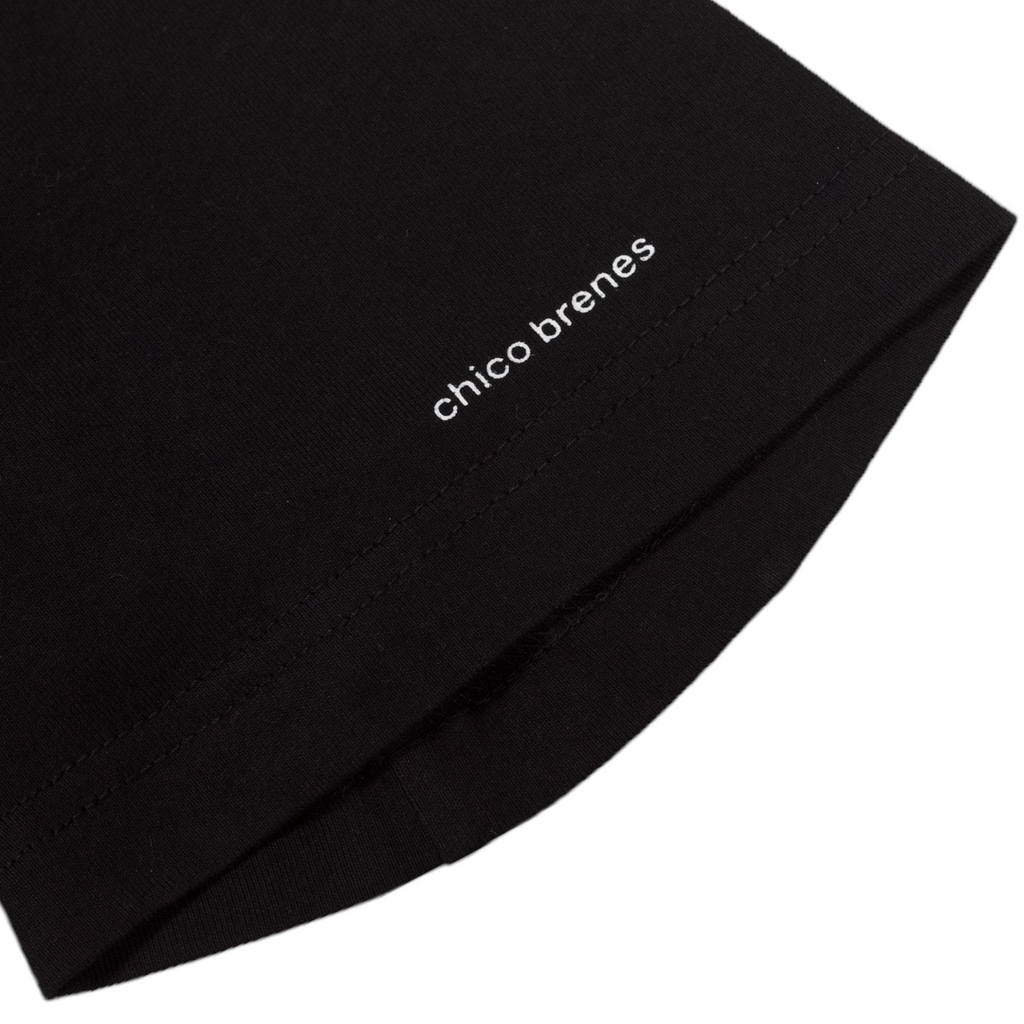 A close up of a white sleeve print on the black tee that says "chico brenes".