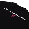 Close-up of a Carpet Co. Brat Tee Black with the white text "a film by Carpet Company" and a rose pink star graphic embroidered on the upper left.