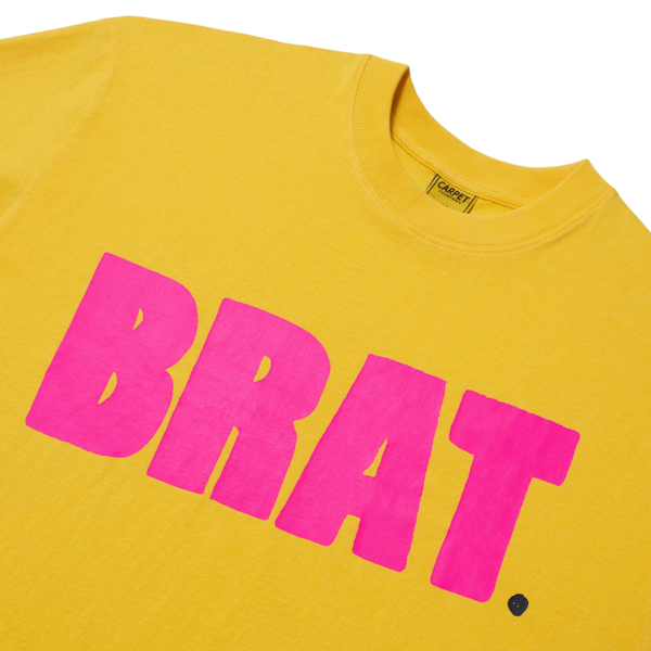 Close-up of a yellow Carpet Co. BRAT TEE LEMON with the word "brat" hand screen printed in large pink letters on the front.