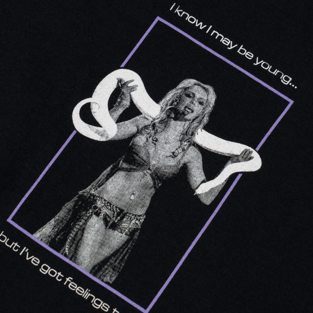 The WELCOME X BRITNEY PRINCESS TEE BLACK features a graphic of a person holding a snake with text above and below the image that reads, "I know I may be young... but I've got feelings too.