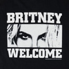 The WELCOME X BRITNEY TILL THE WORLD ENDS TEE BLACK features a black and white graphic showing a close-up of eyes partially obscured by hair, with the text "BRITNEY" above and "WELCOME" below, screen printed on the front.