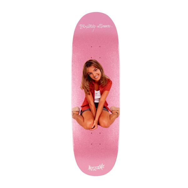 Pink glitter skateboard deck from WELCOME, featuring an image of a young woman sitting cross-legged and smiling, with the text "Birthday Saanz" at the top and "Welcome" at the bottom. Product name: WELCOME X BRITNEY BABY ONE MORE TIME ON BOLINE 2.0.
