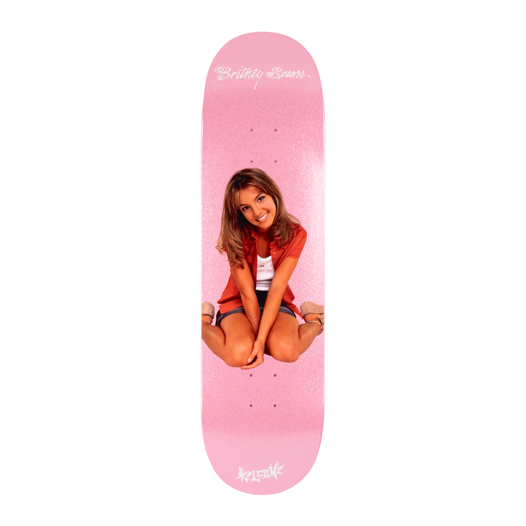 A pink skateboard deck features an image of a seated person, smiling and wearing casual clothes with glitter accents. The name "Britney Spears" is printed near the top, and the brand "WELCOME" is written at the bottom. The product is named "WELCOME X BRITNEY BABY ONE MORE TIME.