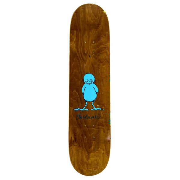 The top brown stain of a skateboard deck that has a printed image of a blue bird and Chico Brenes signature.