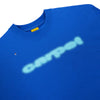 A blue CARPET FLY TEE by Carpet Co. featuring a blurred white "CARPET" logo and a small insect on the left shoulder area, crafted using greenscreen printing for extra detail.