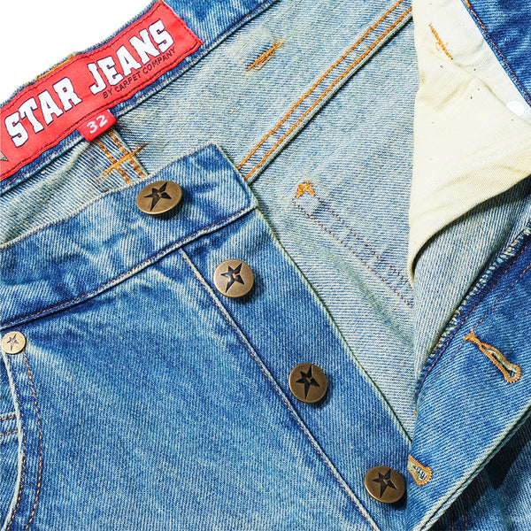 Close-up of classic C Star denim jeans with a red "STAR JEANS" label, brown star-shaped buttons, and orange stitching—ideal to pair with your CARPET CO. C STAR FADED DENIM SHORTS by Carpet Co.