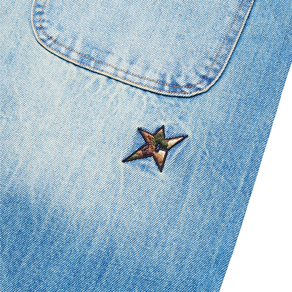 Close-up of Carpet Co. C Star Faded Denim Shorts in light blue, showcasing a camouflage star-shaped patch beneath the pocket seam.