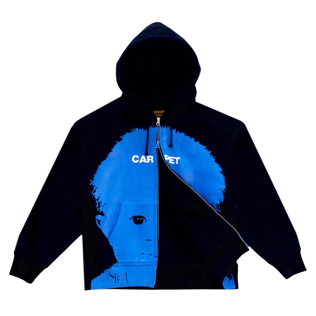 The CARPET CO. BABYPHAT DOUBLE ZIP HOODIE BLACK by Carpet Co. showcases a striking blue graphic of a child's face with "CARPET" printed boldly in white across the chest, blending artistry and comfort seamlessly.