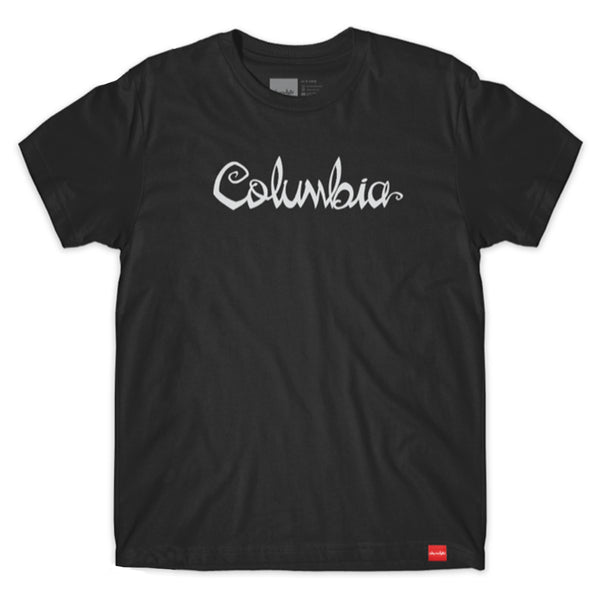 The CHOCOLATE X BLUETILE X COLUMBIA FLIP THE SCRIPT TEE showcases "Columbia" in elegant cursive against a black backdrop, with a subtle red label near the bottom hem. Tailored for those who value understated fashion, this tee is part of the exclusive Chocolate x Bluetile collection, combining style and statement seamlessly.