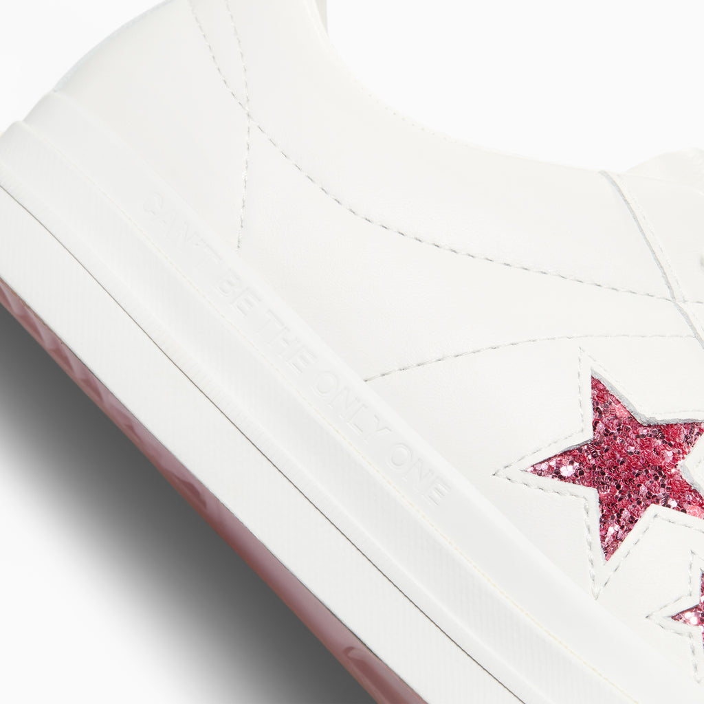 A pair of CONVERSE x TURNSTILE ONE STAR PRO OX WHITE / PINK sneakers with pink stars on them.