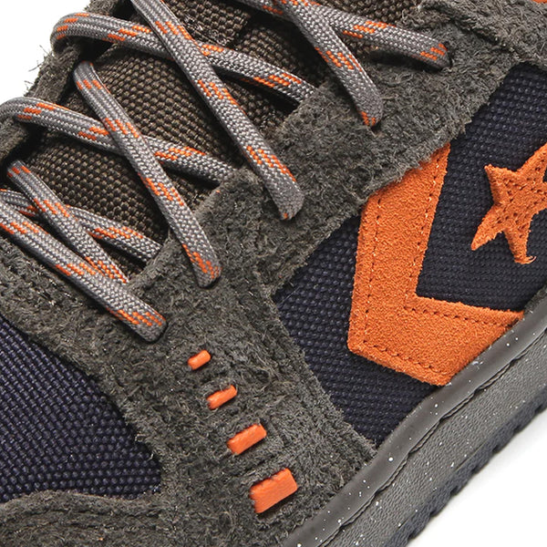 Close-up of a CONVERSE CONS Alexis AS-1 Pro sneaker showcasing textured dark gray Cordura™ suede, vibrant orange accents, and uniquely patterned laces.