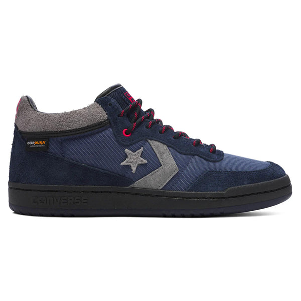 The CONVERSE CONS FASTBREAK PRO MID in Obsidian and Dark Waters features a high-top design with navy blue and gray tones. It showcases a star logo accented in red and includes a sturdy black sole. Equipped with Cordura™ fabric for increased durability, it also features CX cushioning to ensure maximum comfort.