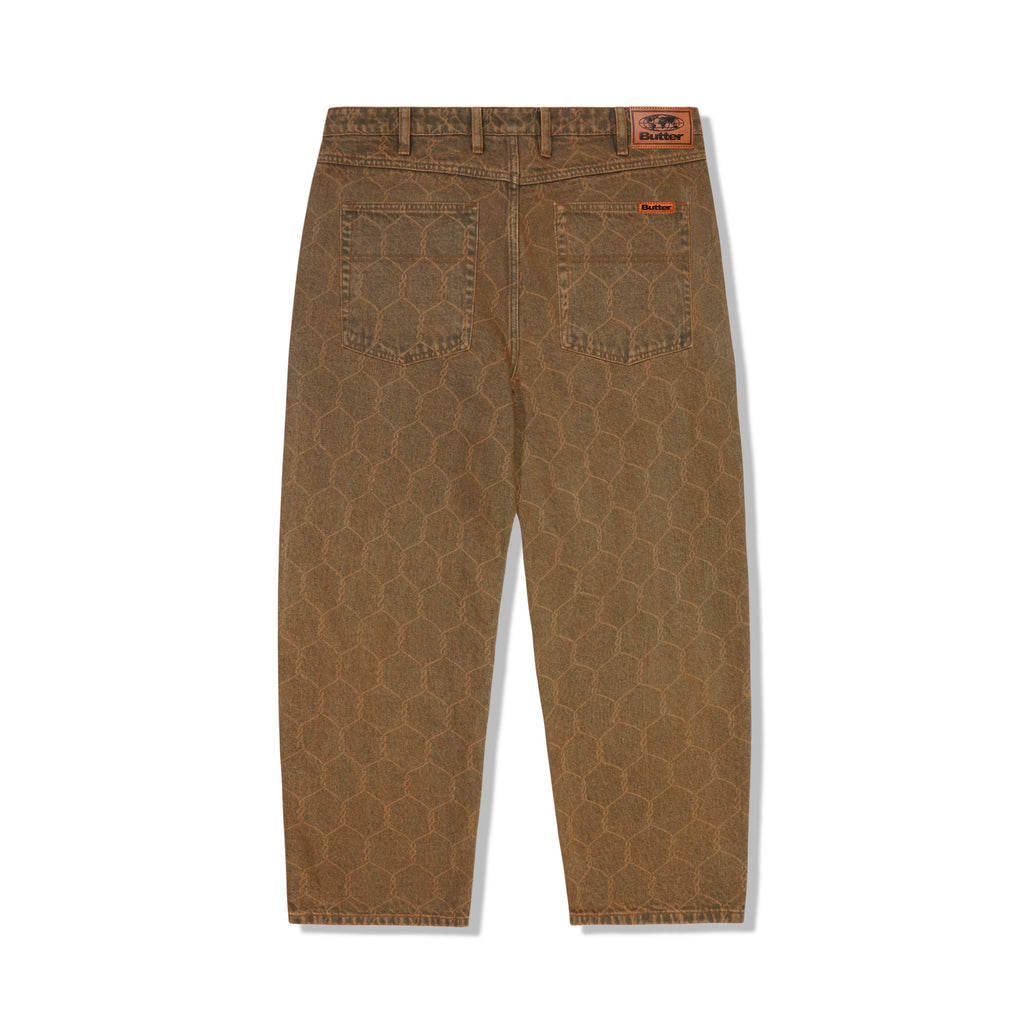 A pair of BUTTER GOODS CHAIN LINK DENIM JEANS WASHED BROWN pants with an orange logo on them.