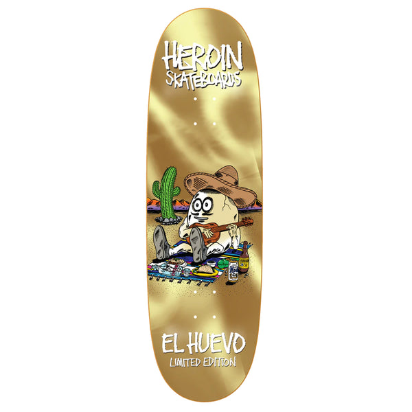 Limited edition "HEROIN EL HUEVO GOLD EGG" custom shape skateboard deck by HEROIN featuring a cartoon egg character, sombrero, and scattered art supplies on a beige background.