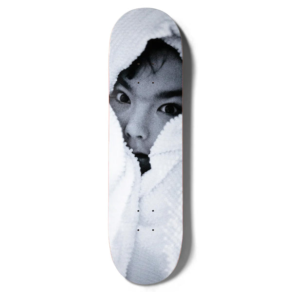 Skateboard deck featuring a black-and-white image of a person's partially covered face peeking out from a blanket, reminiscent of Photo Kim Gordon's iconic style, called GIRL SPIKE PHOTO BJORK by GIRL.