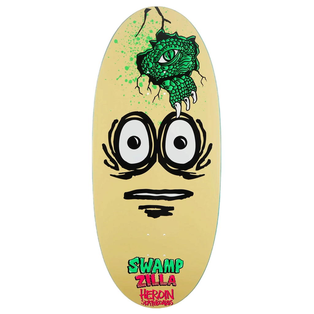 The HEROIN SWAMPY PRO EGG SWAMP ZILLA skateboard deck features a striking graphic of two wide eyes and a gaping mouth, with a green reptilian claw and eye emerging from a cracked opening above. The design includes the text "SWAMP ZILLA" and "HEROIN SKATEBOARDS." Crafted from North American Hard Rock Maple, it guarantees razor edge performance.