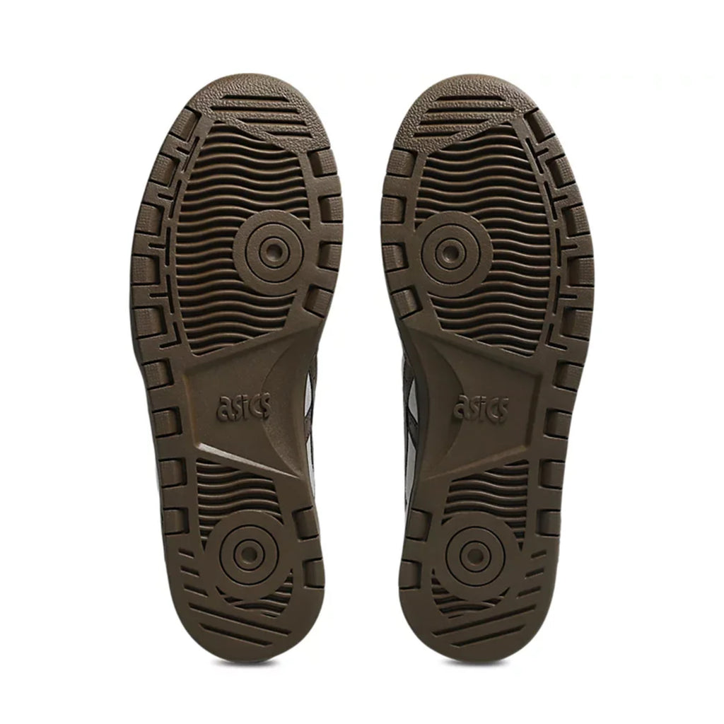 The image shows the soles of ASICS JAPAN PRO CLOUD GREY / BROWN STORM sneakers, featuring grooved and circular tread patterns for grip and durability, enhanced by subtle suede panels—ideal for skateboarding.