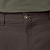 Close-up of a person wearing DICKIES Jamie Foy Loose Fit Straight Leg Pants in Dark Brown with a brass button and a tucked-in green shirt. The straight leg fit and brushed twill fabrication add to the stylish yet comfortable look.