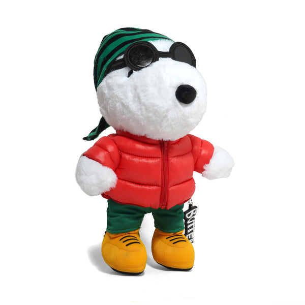 The BUTTER X PEANUTS JOE GRUNGE PLUSH by Butter Goods features Snoopy in a red puffer jacket, green pants, yellow shoes, sunglasses, and a green striped bandana—an eye-catching polyester plush on a white background.