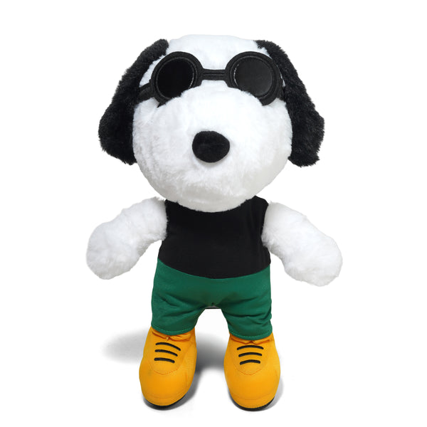 The BUTTER X PEANUTS JOE GRUNGE PLUSH by Butter Goods features a plush dog key chain in round black sunglasses, black shirt, green pants, and yellow shoes standing upright against a white background.