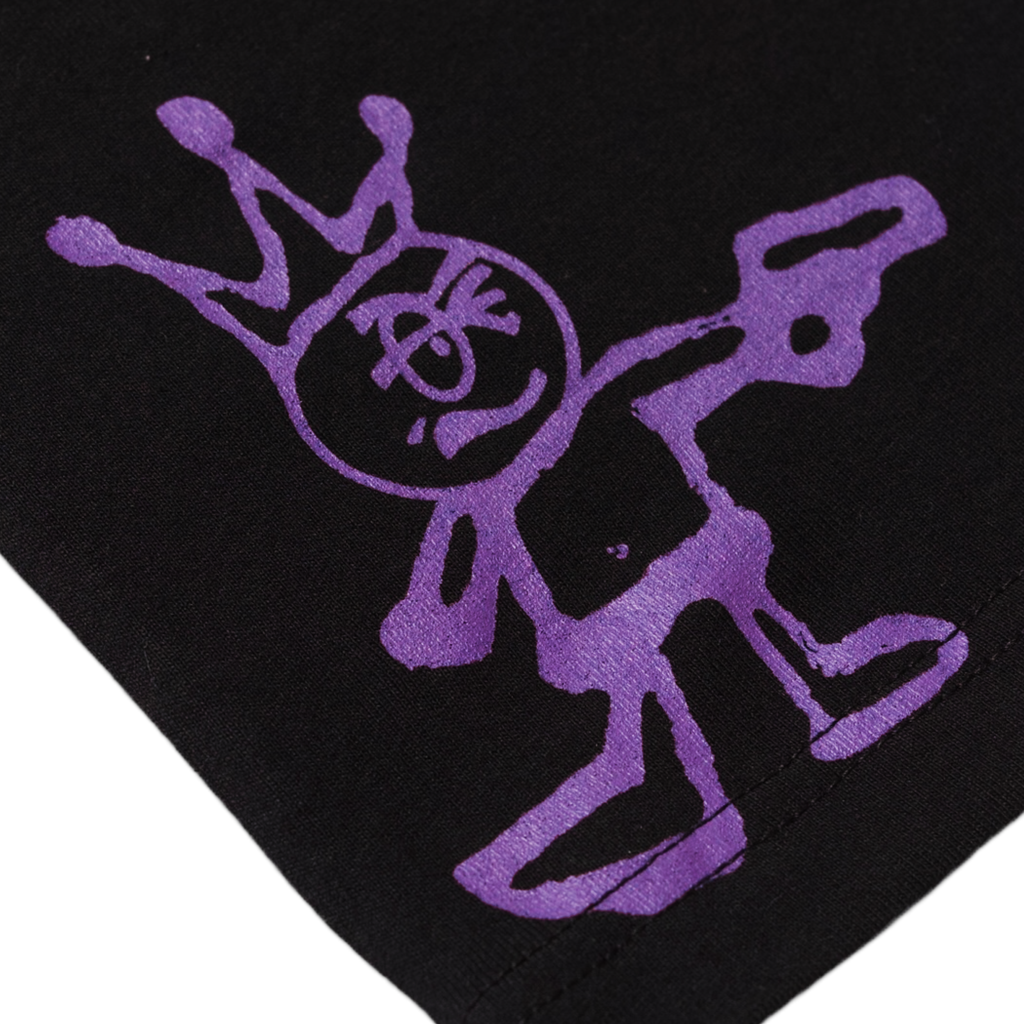Close-up of a purple graffiti-style drawing of a stick figure with a crown, spray-painted on a Carpet Co. "Kid" Tee Black background.