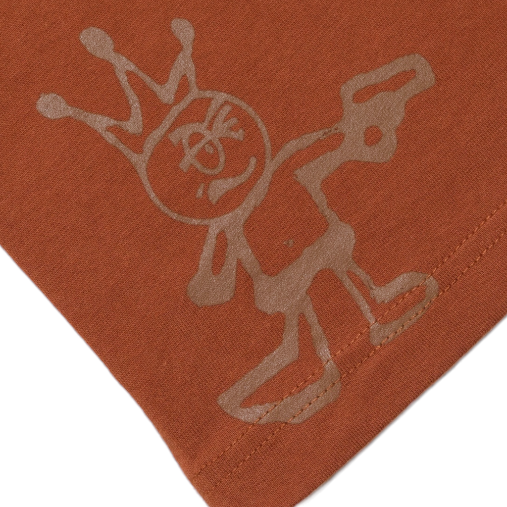 A whimsical stick figure with a smiling face and a crown, screen printed in white on a rust-colored CARPET CO. "KID" TEE BROWNfabric background.