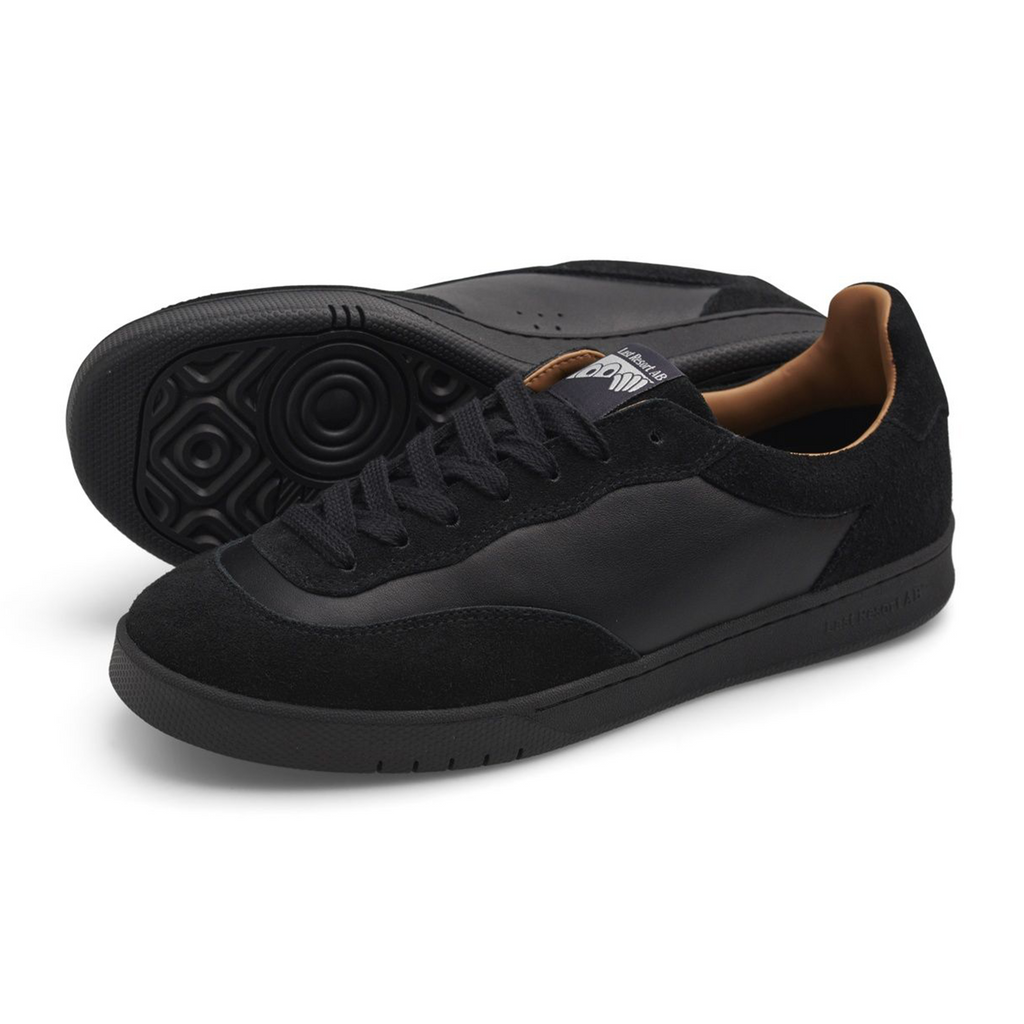 A side view of an all black shoe with leather and suede paneling.