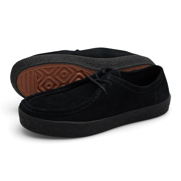 A pair of LAST RESORT AB VM006 MOC BLACK / BLACK suede shoes from Last Resort AB, featuring a Suede Upper and a thick black Rubber Sole with brown tread patterns, one shoe standing and the other lying on its side.