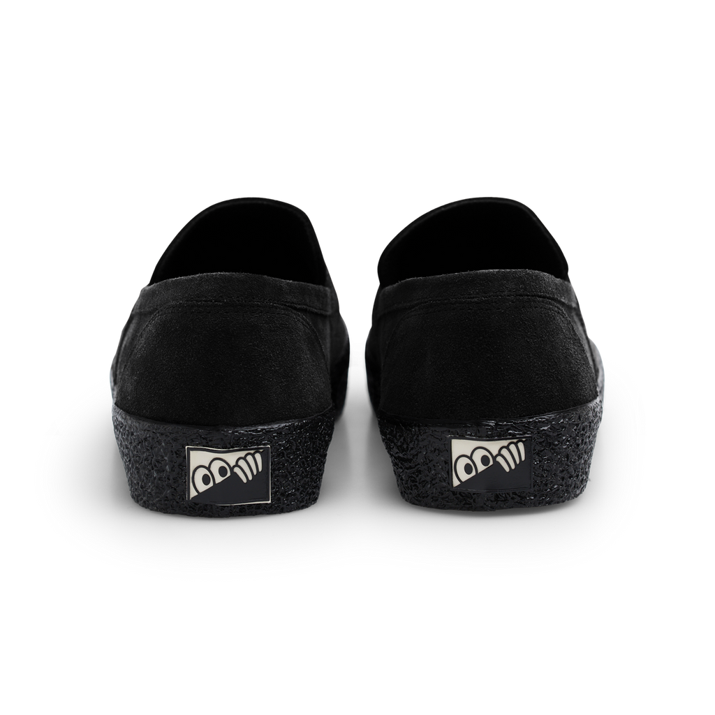 A pair of Last Resort AB black slip-on shoes with a suede upper and a logo on the side.