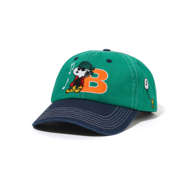 The BUTTER X PEANUTS MUSIC SNAPBACK CAP by Butter Goods features Snoopy in sunglasses, an orange "B", musical notes, and Woodstock embroidered on a washed kelly green and navy snapback.