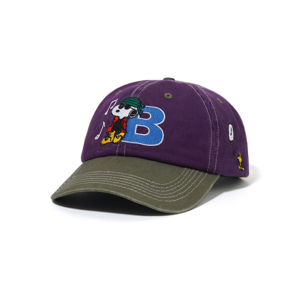 The Butter Goods BUTTER X PEANUTS MUSIC SNAPBACK CAP in washed purple/fern features cotton twill, direct embroidery of Snoopy with headphones, a blue "B," and yellow and white side designs.