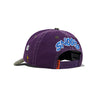 The BUTTER X PEANUTS MUSIC SNAPBACK CAP in washed purple by Butter Goods features "SNOOPY" embroidered in blue and white on the back, an eye graphic on the side, and an adjustable strap for a perfect fit.