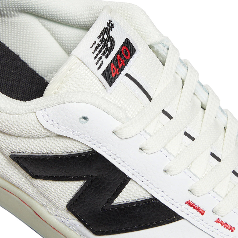 Close-up of the NB NUMERIC 440 V2 WHITE / BLACK: a white skate shoe with a black "N" logo, white laces, and a tongue label reading "NB 440" in black and red—ideal for everyday skaters.