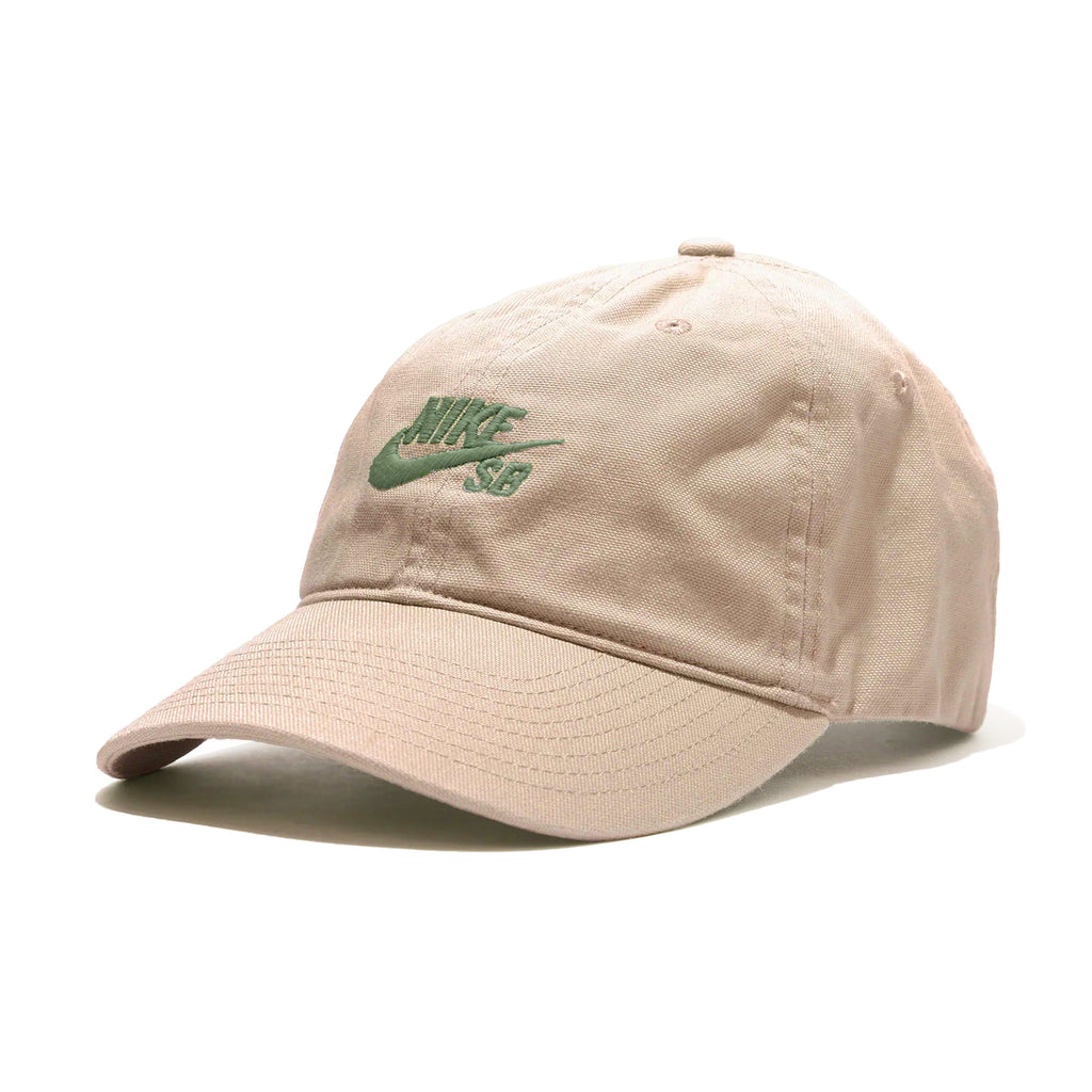 A beige NIKE SB CLUB HAT GUAVA ICE / NEUTRAL OLIVE with a green Nike SB logo embroidered on the front, crafted from durable cotton twill fabric and featuring an adjustable back strap.