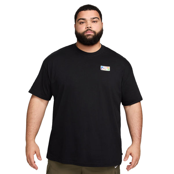 A bearded man in a black Nike SB Forecat Skate Tee and khaki pants standing against a white background.