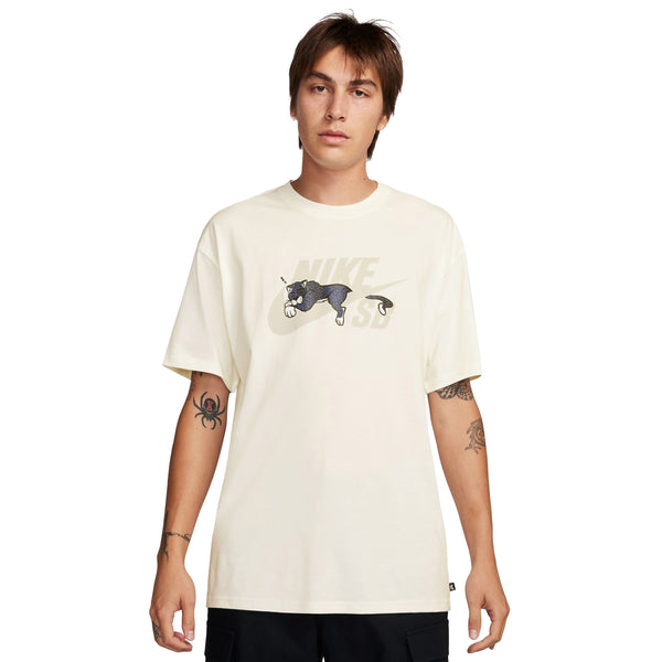 A young man wearing a beige Nike SB Panther Skate Tee Sail t-shirt with a graphic of a panther, standing against a plain background.