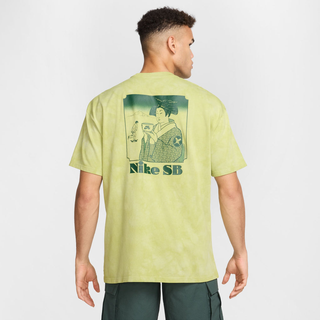 A person is wearing a Nike SB Yuto Horigome Skate Tee in olive aura, featuring an illustration of a traditional figure and "Nike SB" text on the back.