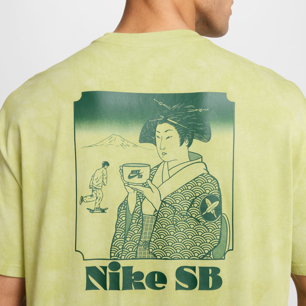 A person wearing a NIKE SB YUTO HORIGOME SKATE TEE OLIVE AURA displays traditional Japanese art while someone sips from a nike cup, and a skateboarder glides effortlessly in the background.