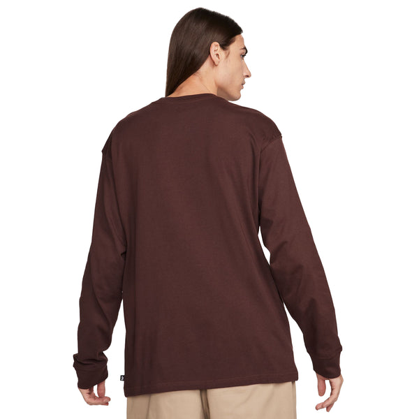 Man wearing a brown Nike 'City of Love' LS skate tee Earth, viewed from the back.