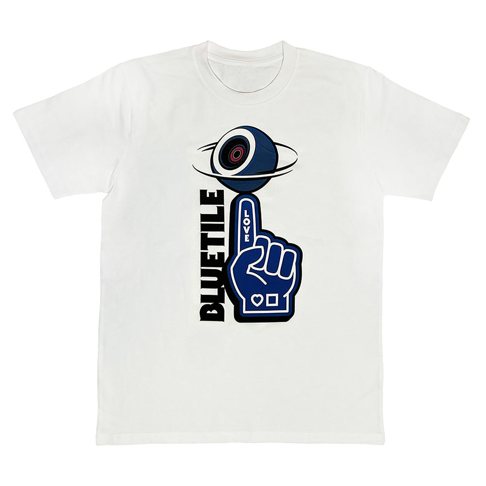 The *PRE-ORDER* BLUETILE NAVY FOAM FINGER TEE WHITE by Bluetile Skateboards is made of 100% cotton, featuring a dark blue eye graphic above a vibrant blue foam finger with "LOVE" and vertical BLUETILE text on the left side.