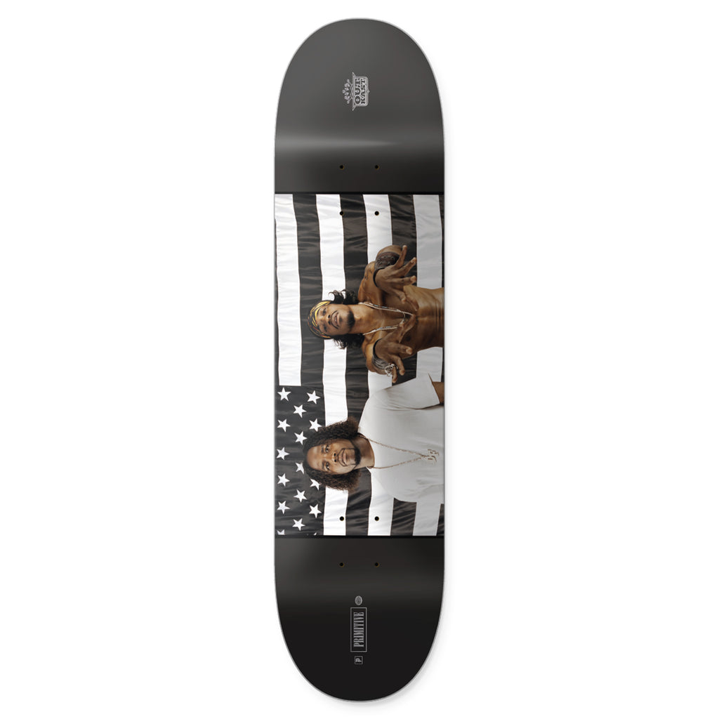 Skateboard deck from PRIMITIVE, named PRIMITIVE X OUTKAST STRIPES, featuring a black and white American flag design with two people honoring Outkast's iconic style.