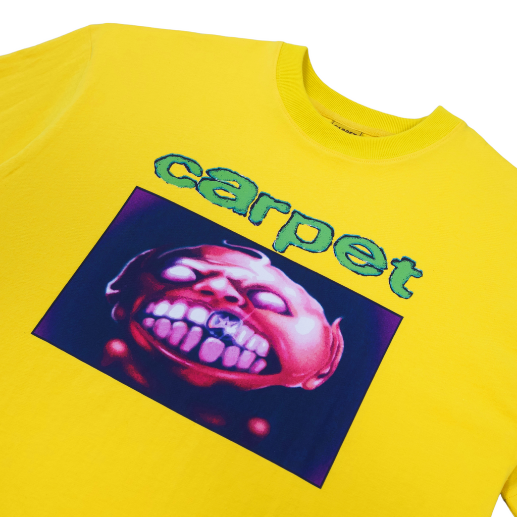 A close up of a yellow tshirt with the word "carpet" and an image of a character showing its teeth