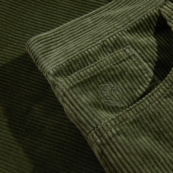 Close-up of the POLAR BIG BOY CORD UNIFORM GREEN fabric with a visible front pocket and a small stitched logo on the pocket, showcasing its high-waisted design.