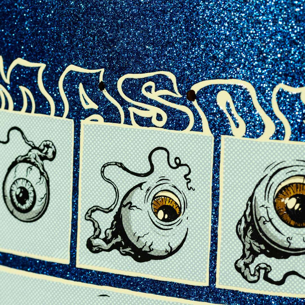 The REAL MASON 4TH WALL GLITTER by REAL features illustrated eyeballs with tendrils against a glittery blue backdrop, evoking the edgy appeal of a skateboard graphic, with partially visible white lettering.