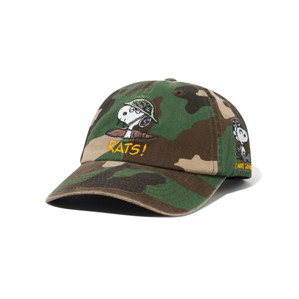 The BUTTER X PEANUTS RATS 6 PANEL CAP WASHED CAMO by Butter Goods features embroidered Snoopy graphics, "RATS!" text on the front, and "I LIKE OPS!" text on the side.