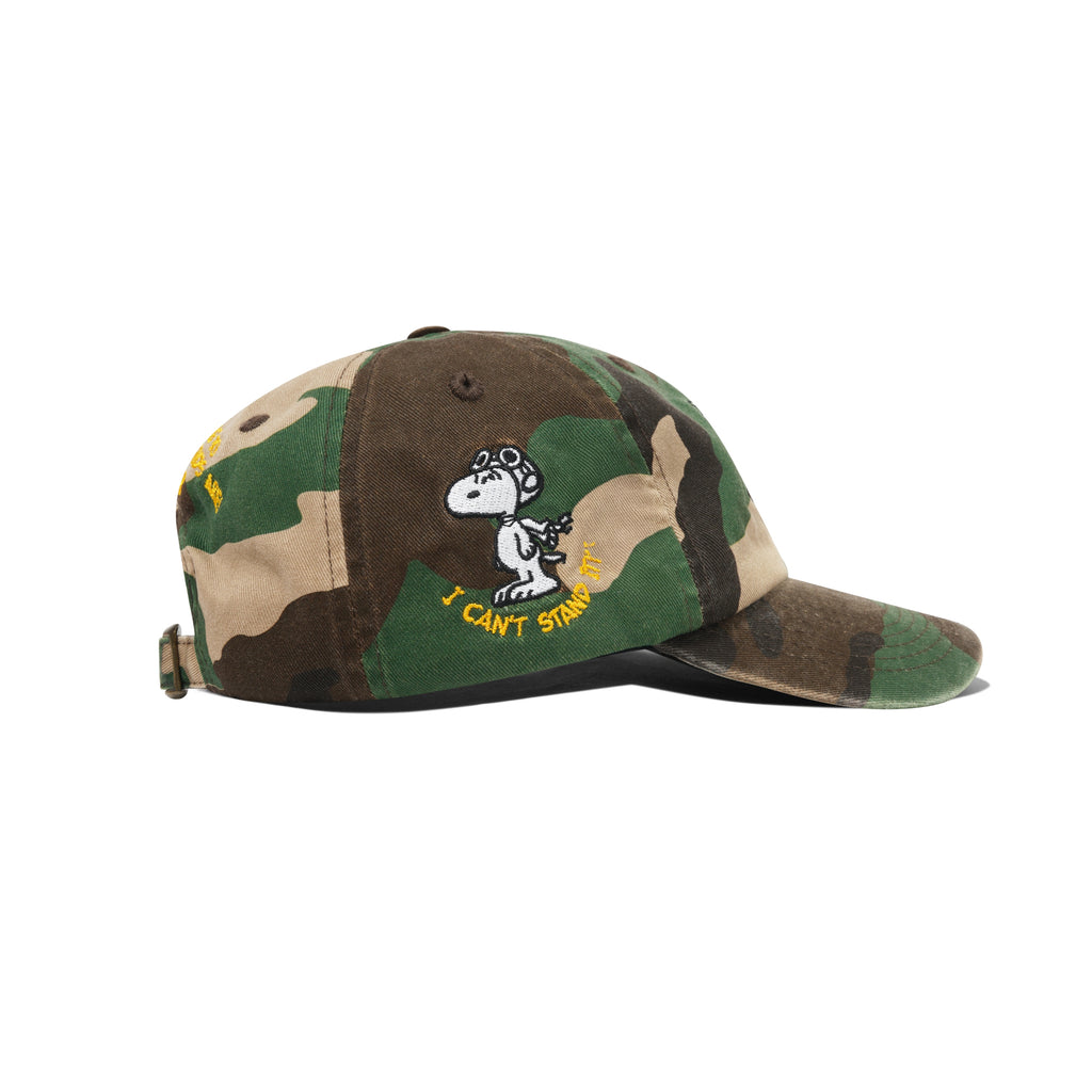 The BUTTER X PEANUTS RATS 6 PANEL CAP WASHED CAMO by Butter Goods features a washed camo design, Snoopy embroidered in aviator gear, and "I CAN'T STAND IT!" text on the side.